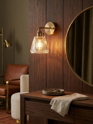 Aurelia wall sconce glowing beside a vanity mirror
