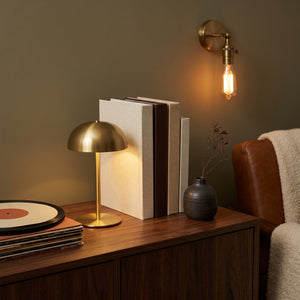 Pico brass mushroom table lamp on a walnut credenza with the Hayden brass wall sconce
