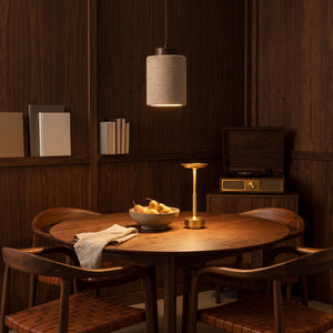 Sora stone pendant light over a walnut dining table with the Margo gold cordless lamp