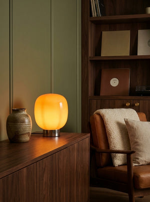 Bruno rounded glass lamp glowing on a walnut console