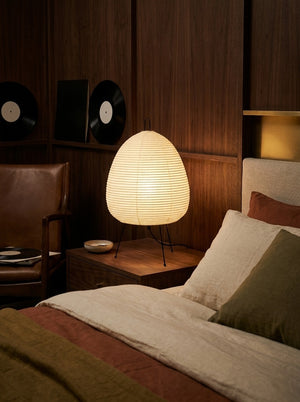 Kumo lamp beside a linen bed at night